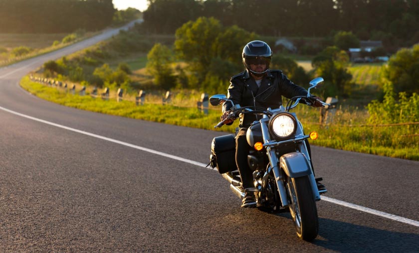 Guy riding motorcycle on country road